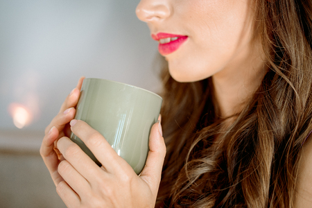 Young sexy girl in the morning sits on the kitchen table. A girl in purple lingerie drinks tea in a bright white kitchenの写真素材