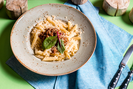 Italian spaghetti on rustic wooden table. Mediterranean cuisine with pasta ingredients- bolognese sauce, olive oil, basilの写真素材