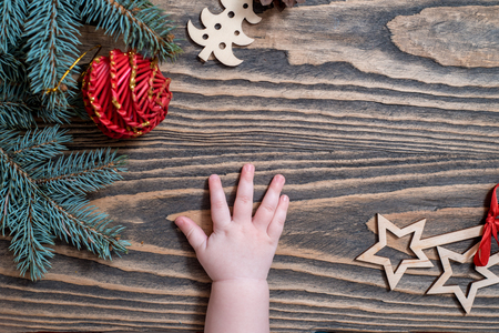 children's hands on a wooden background. Christmas Card. green tree, red balls, sweet lollipops. The child takes Christmas candy from the table. White snowflakes. Flat lay, top view. copy space.の写真素材
