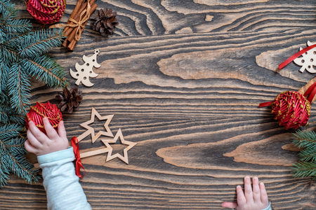 children's hands on a wooden background. Christmas Card. green tree, red balls, sweet lollipops. The child takes Christmas candy from the table. White snowflakes. Flat lay, top view. copy space.の写真素材
