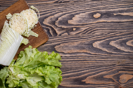 Fresh green Lettuce, cabbage, sweet red pepper on a wooden background. Vegetarian vegetables for cooking salad. Diet and healthy nutrition. copy spaceの写真素材