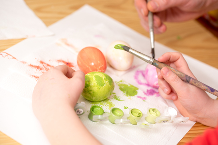 Close up of kid ' s hand holding an ester egg during painting. Happy ester concept.の写真素材