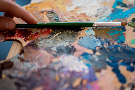 artist paints a picture of oil paint brush in hand with palette closeupの写真素材
