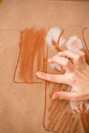 Collection of rainbow colored pastel crayons with crushed chalk on old wooden desk.の写真素材