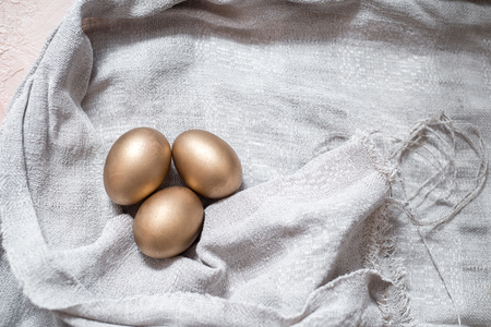 golden easter eggs. In the nest. gray linen tablecloth. easter concept, or the concept of wealth and individualityの写真素材