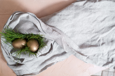 golden easter eggs. In the nest. gray linen tablecloth. easter concept, or the concept of wealth and individualityの写真素材