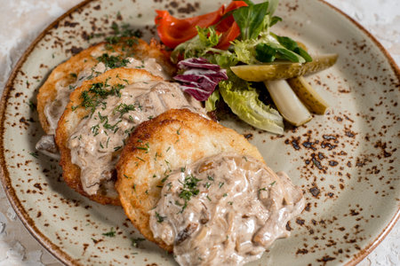 Potato pancakes in white mushroom sauce. Draniki - potato fritters. Vegetable fritters, latkes,...