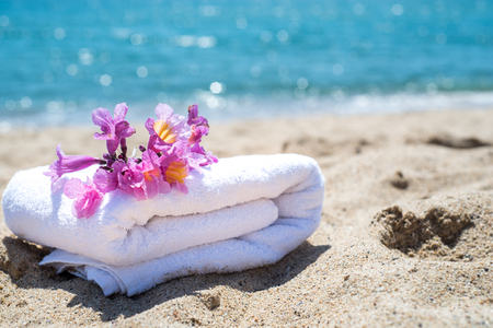 White towels and purple flowers with ocean. Stacked white spa towels on the blue Indian ocean background. Maldives luxury resort vacation. white towels on sea. Vacation, relaxation and spa conceptの写真素材