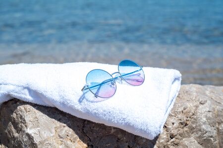 sunglasses lying on tropical sand beach. white towel . Sunglasses on the beach. Beautiful sea view wallpaper, background. copy cpaseの写真素材