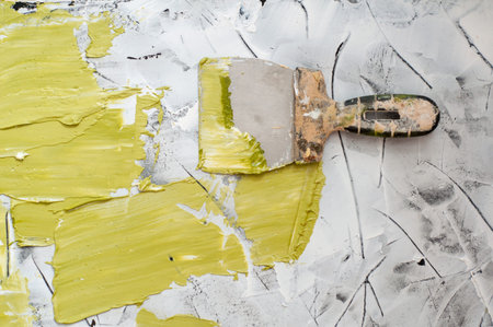 Hand with green olive putty knife repair wall, Hand with a spatula, spatula with Spackle paste structure, process of applying layer of putty trowel. Copy spaceの写真素材