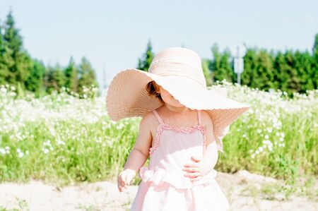 Happy cute baby girl in a field with daisies.の写真素材