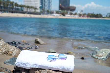 sunglasses lying on tropical sand beach. white towel and glasses with seashells. Sunglasses on the...