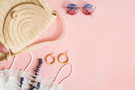 Fashionable Lady's Accessories. summer woven eco bag made of straw, eco friendly bamboo earrings, Eyelashes for eyes, purple lavender flowers. Detail Fashion on a pink background. copy space. flat layの写真素材
