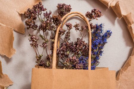 Kraft package, reusable environmental packaging, homemade tea flowers. mint lemon balm and hyssop. Torn paper as background. hole in kraft paper. Flat Lay Copy spaceの写真素材