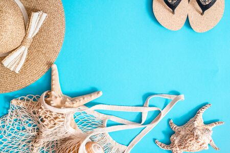 Accessories for summer on bright blue background. Summer hat, beach sandals, shopping bag with shells and starfish. Creative flat lay.Top view. copy spaceの写真素材
