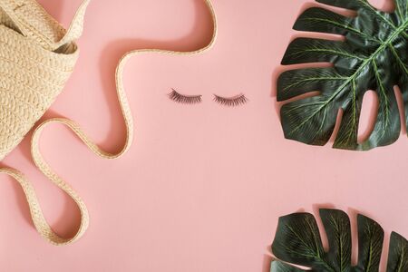 Pink office table, Woman's accessories,Eyelashes for women, eco straw bag, natural bamboo earringswriting concept. Top view, flat lay, space for text.の写真素材