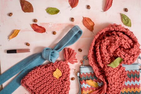 Hygge style autumn composition with bright warm clothes, felt hat, dry yellow leaves and striped decorative pumpkins on wooden rustic background. Lagom concept. Halloween composition.の写真素材