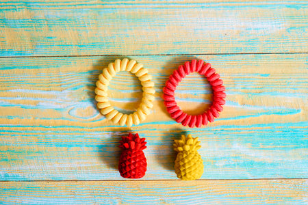 Flat lay of yellow and red pineapple fruit toy on on blue and yellow wooden old background minimal...