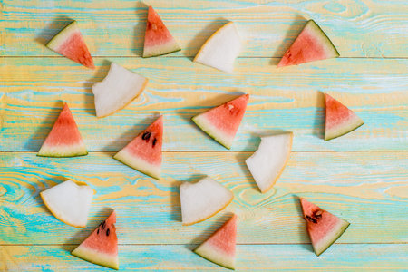 Pieces of watermelon and melon on blue and yellow old wooden background. Summer concept. Flat lay,...