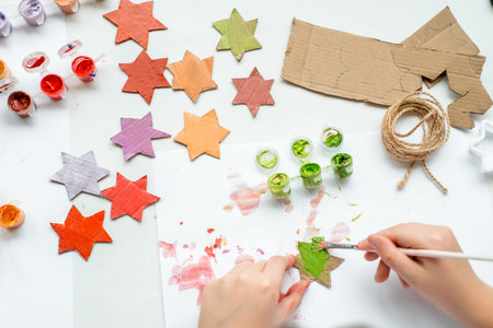 The child makes crafts for the new year. Cardboard Christmas tree stars. Zero waste