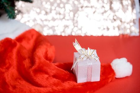 Christmas white gift box with a large bow standing on red hat santa clausの写真素材