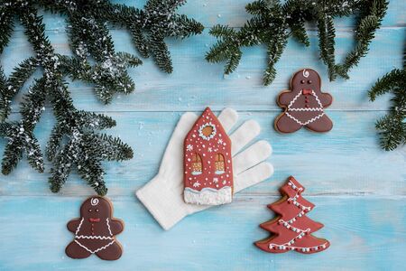 Christmas gingerbread on a white mitten. on a blue wooden background. New Year card. Christmas tree with balls and a house.の写真素材