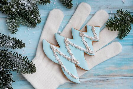 Christmas gingerbread on a white mitten. on a blue wooden background. New Year card. Christmas tree with balls and a house.の写真素材