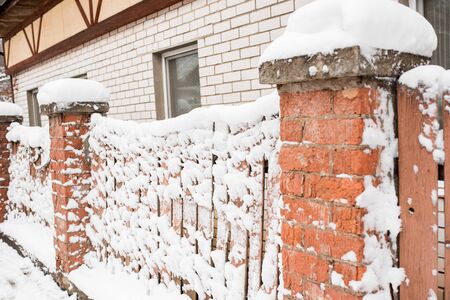 Winter in the village. Wooden frozen fence. Snow and icicles are everywhere. New Year and Christmas mood. Severe frost. Ice in the puddles. Slippery roadsの写真素材