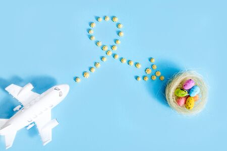 plane flies on blue background.yellow sweets. Direction sign for easter eggs. Spring and Easter are coming.Beautiful creative arrow made of colored eggs. Pointer or cursor from eggs. Top view flatの写真素材