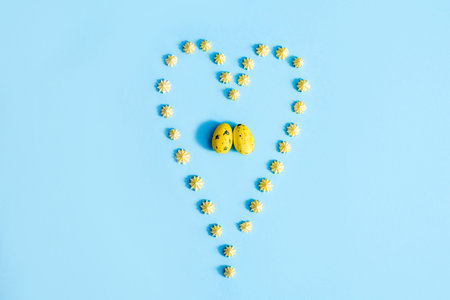 Easter Eggs. Yellow eggs on a blue background. heart made of sweet sweets. Two eggs, a symbol of...