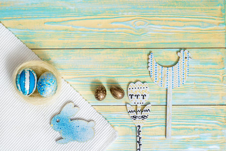Easter decoration on a blue wooden background. Blue eggs, wooden rabbit and chicken painted by...