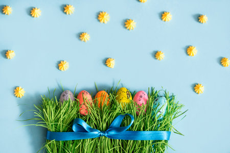 Fresh green spring grass border. easter decoration. colored eggs on green grass. blue ribbon and...