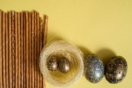 Golden easter eggs on a yellow background. blue napkin. salty cookies and cracker.Easter concept. copy space. Flat lay, top view, trendy modern celebration styleの写真素材