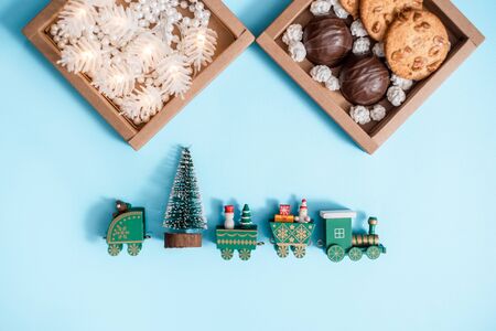 Handmade gift box with house cat toy on blue background as a present for Christmas. Sweet candies and chocolate chip cookies in a craft box. Baby hands bring presents.White sweet snow.Flat layの写真素材