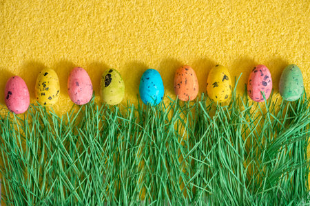 colorful easter eggs on green grass in Springtime. Easter card, colored eggs, yellow background,...