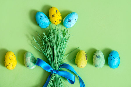 Easter background with eggs and bouquet of green grass and colored easter eggs. Holiday Flat lay...