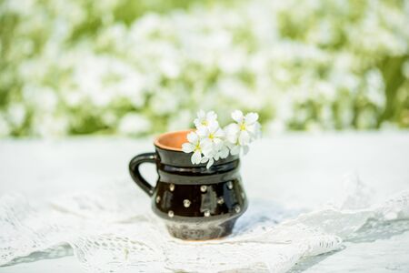 Black clay mug, sunny summer, wildflowers in a vase on a lace knitted tablecloth, lace. A village and vintage, a gentle cozy morning, flowersの写真素材