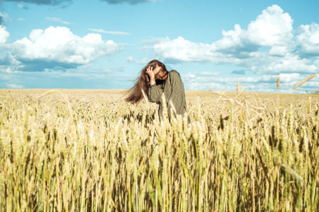 ears of wheat. young girl in dress shows emotion. emotionally jumps and runs on a summer field with...
