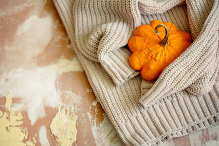 Hello fall. Cozy autumn image. yellow pumpkins, autumn leaves on knitted sweater on rustic wood. Happy Thanksgivingの写真素材
