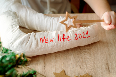 boy with plaster cast on his arm makes Christmas crafts. Hand fracture and injury. Removes plaster cast, waiting for a new life. New year and new plans.の写真素材