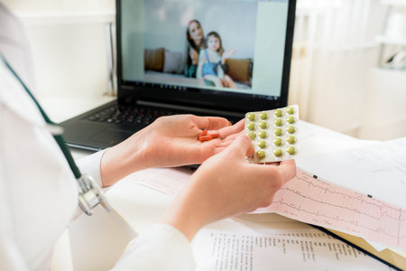 Close-up Of A Woman Video Conferencing With Female Doctor On Laptop.online pediatrician consultation. Mom and baby in her arms talking via video.offer of treatment, pills in handsの写真素材
