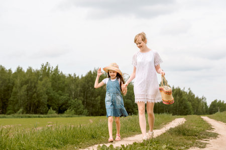A walk Family in the forest along the path of outdoor.Young mother and her little daughter at beautiful autumn park. Kid girl and beautiful woman in gumboots walking and having funの写真素材