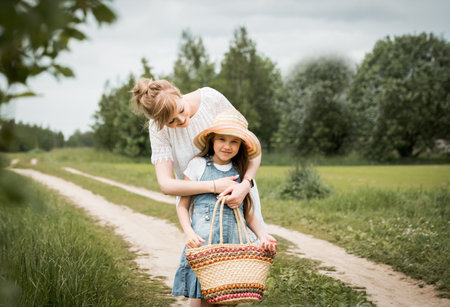 mother and daughter walking in the forest and holding hands.walk along the path. field and nature. Wicker basket. maternal love, happy childhood.mom hugs a girl, care and education, family concept.の写真素材