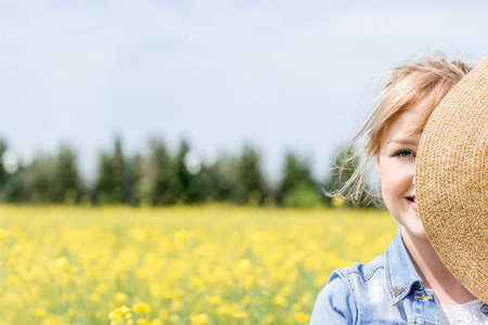 Portrait of a happy cute girl, summer wheat field, in white dress and hat.yellow rapeseed flowers....