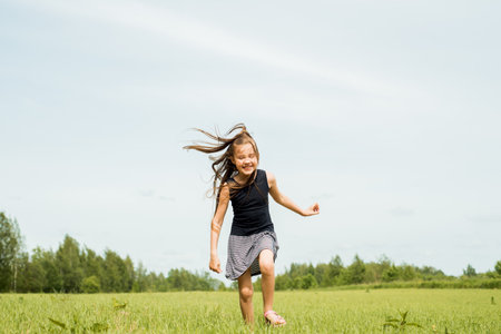 Girl, jumping in the field.running and jumping. happy childhood, hot summers, freedom and lifestyle. wind in hairの写真素材