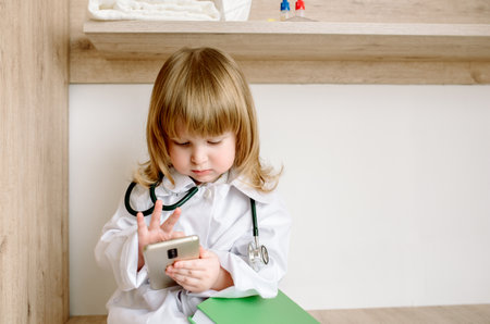 baby girl uniformed as doctor writing to clipboard.Medical gown and phonendoscope. The doctor is calling.の写真素材