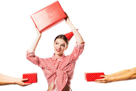 Joyful girl, party . Gorgeous slim young woman wearing in a striped red shirt, having fun. Lots of red gift boxes, surprise for birthday On a white background in the studio. party concept.の写真素材