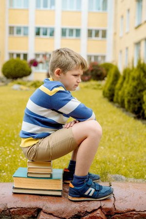 Portrait of Beautiful school boy looking very happy outdoors at day time. Sitting on the steps with...