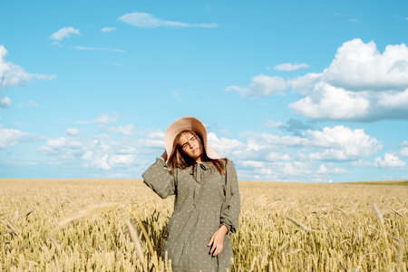 young woman in white dress, straw hat , flower field,ears of bread.の写真素材
