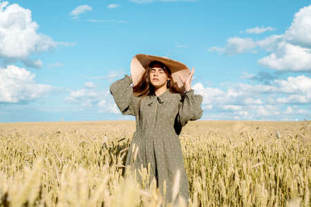 young woman in white dress, straw hat , flower field,ears of bread.の写真素材